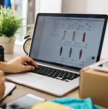 Person using a laptop and smartphone to make an online purchase, representing the implementation of custom logistics software for improved real-time order tracking and inventory management in e-commerce, resulting in increased customer satisfaction and operational efficiency.