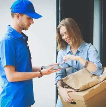 Delivery person handing a package to an elderly man at his front gate, symbolizing the use of transportation management software for real-time tracking and route optimization in postal and courier services to improve delivery efficiency.