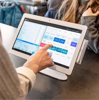 Retail worker using a point-of-sale system with inventory management software, representing logistics solutions for improving inventory control, enhancing supply chain transparency, and optimizing customer service in retail businesses.