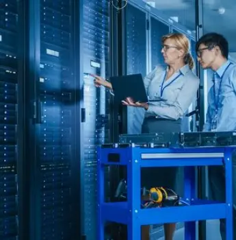 IT professionals deploying software in a server room, representing the offshore development team's process of transferring the finalized software solution to the client's production environment after testing.