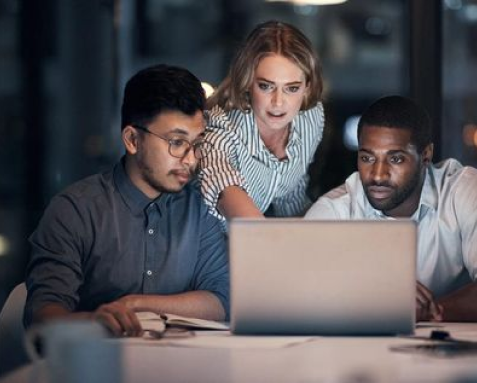 Three team members collaborating on a laptop, evaluating the technical feasibility and system architecture in DevOps managed services.