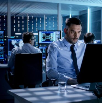 IT professional monitoring systems in a control room, representing the scalability and flexibility of DevOps managed services in adapting to changing workloads.