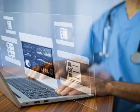 Healthcare professional using a laptop with digital medical records and data analytics displayed on the screen, representing offshore software development services that enhance patient care, operational efficiency, and regulatory compliance in the healthcare industry.