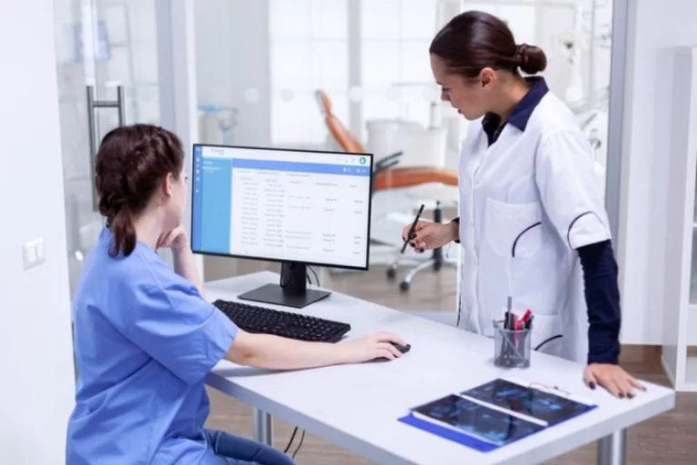 Two healthcare professionals using a computer to manage patient records, illustrating Samyak Infotech's development of a secure and compliant patient management system with AngularJS, enhancing operational efficiency and patient satisfaction for a healthcare provider.