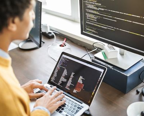 A developer working on a laptop with code on the screen, highlighting Samyak Infotech's maintenance and support services for updating and optimizing AngularJS applications to enhance productivity and stay competitive.