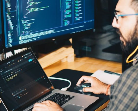 A developer working on code with multiple screens, representing Samyak Infotech's AngularJS migration services for upgrading to the latest version with improved scalability and performance.