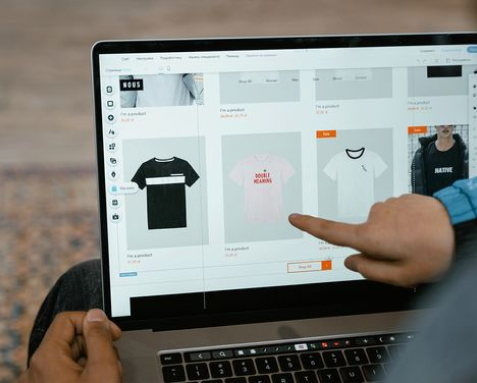Person pointing at a laptop screen displaying an e-commerce website with various products, showcasing secure and user-friendly e-commerce solutions developed by an IT outsourcing company. The platform integrates secure payment gateways, inventory management, and personalized shopping experiences to maximize online sales and customer satisfaction.