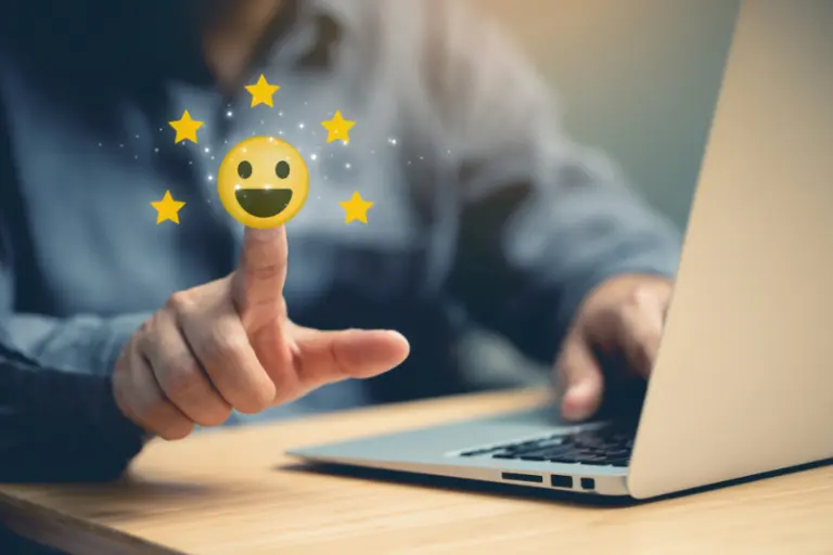 Person interacting with a laptop and a floating smiley face with stars, representing MuleSoft developers integrating CRM systems with communication channels to improve customer experience in telecommunications.