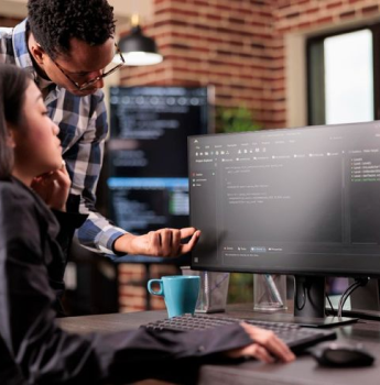 Two developers collaborating on a project, using a computer screen displaying code, emphasizing the strong community support and resources available for Flutter development at Samyak Infotech.