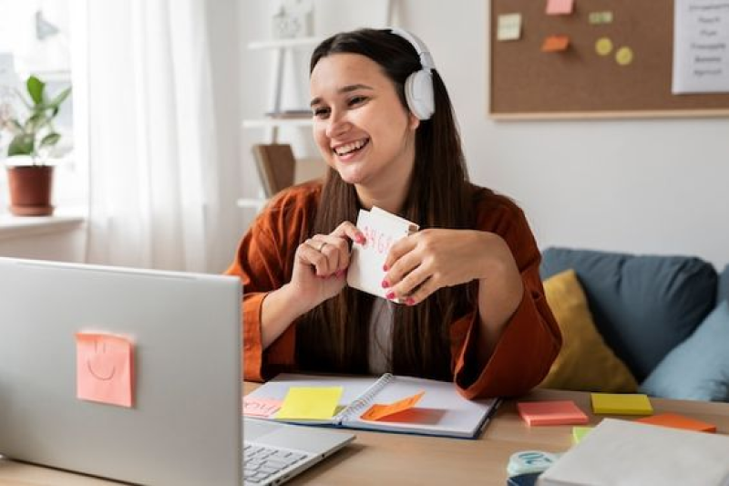 Smiling woman with headphones engaging in an online lesson on a laptop, representing Samyak Infotech's development of an AngularJS-based e-learning platform with video lectures, quizzes, and progress tracking, increasing user engagement for an online education platform.