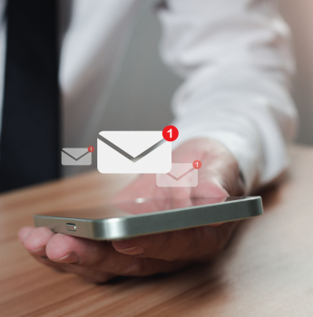 Close-up of a hand holding a smartphone with notification icons for emails, illustrating the integration of native features like push notifications into mobile apps for better user experience.