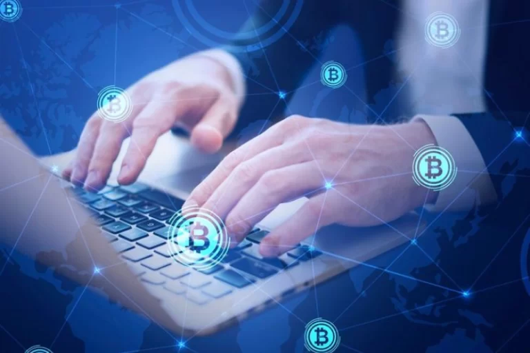 Hands typing on a laptop with digital Bitcoin symbols connected by lines overlaying the image, representing blockchain technology in logistics.