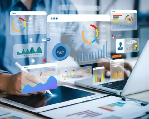 Person using a tablet and laptop with floating data charts and graphs, representing real-time visibility and insights through configurable dashboards and reports using MuleSoft.