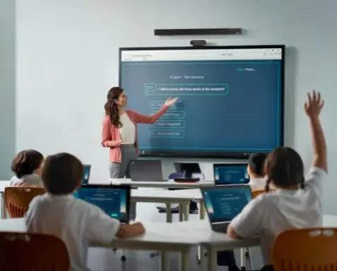 A teacher standing in front of a smartboard in a classroom with students, showcasing the use of Power Automate services to automate student enrollment and attendance tracking in the education sector for enhanced efficiency and communication.