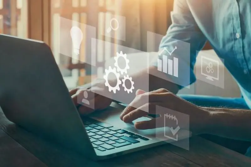 A person typing on a laptop with overlay icons of gears and charts, symbolizing the use of Power Automate services to reduce administrative workload and improve workflow efficiency in educational institutions.