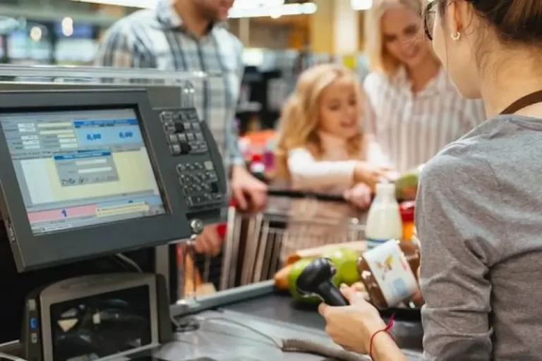 A cashier scanning items at a checkout counter while a family waits, illustrating the use of Power Automate consulting services to improve customer support efficiency in retail by reducing response times and increasing satisfaction.