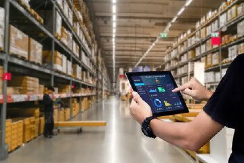 A person using a tablet to manage inventory in a large warehouse, displaying analytics and data on the screen, representing custom AI solutions for improving inventory management and boosting customer engagement in the retail industry.