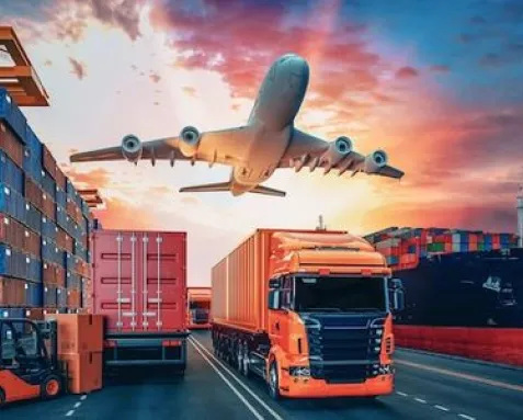 An airplane flying above trucks and shipping containers at a port, representing machine learning development services for optimizing supply chains, predicting demand, and managing logistics operations for enhanced efficiency and cost reduction.