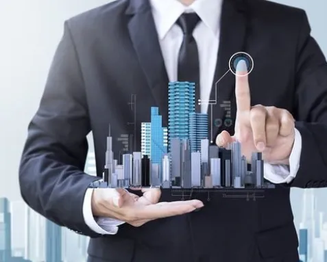 Business professional in a suit interacting with a digital model of a cityscape, symbolizing offshore software development services transforming the real estate industry with advanced technologies like AI-driven property management and virtual staging.