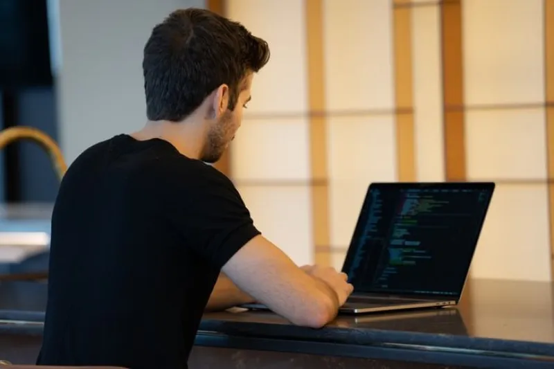 Developer working on a laptop in a modern workspace, showcasing cost-effective solutions provided by a leading offshore software development company in the USA without compromising quality.